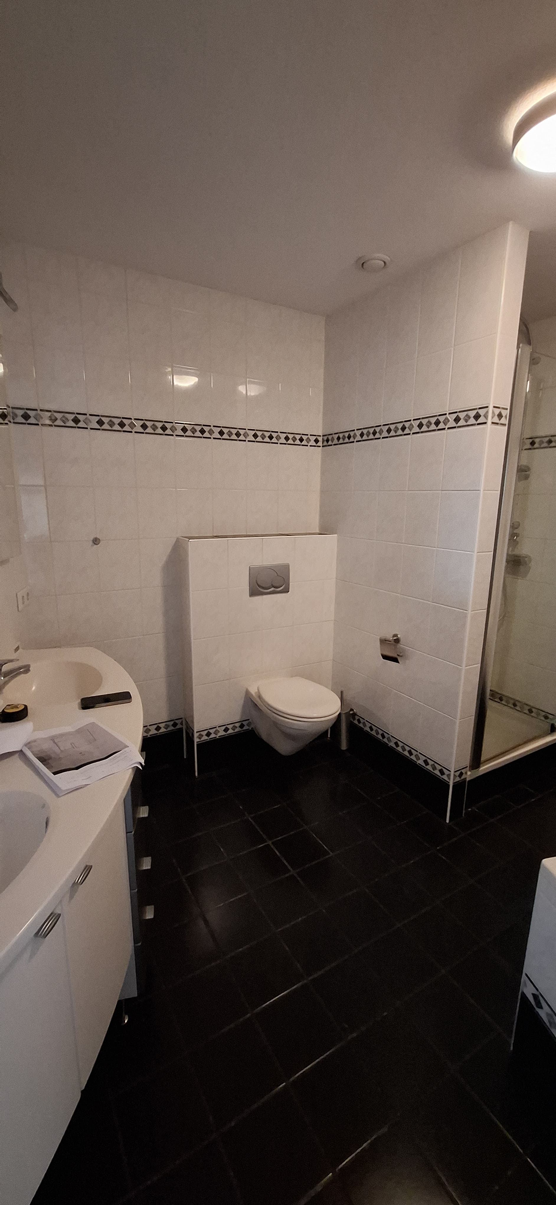 Gedateerde badkamer met wandcloset, wastafel en douchecabine voor renovatie